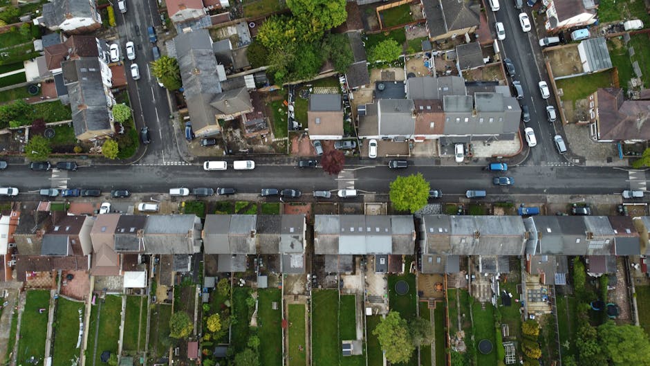 An aerial view of a residential street in Field End Road, Eastcote, showing a row of terraced houses with small, well-maintained gardens at the back. Each garden features lush green lawns, flower beds